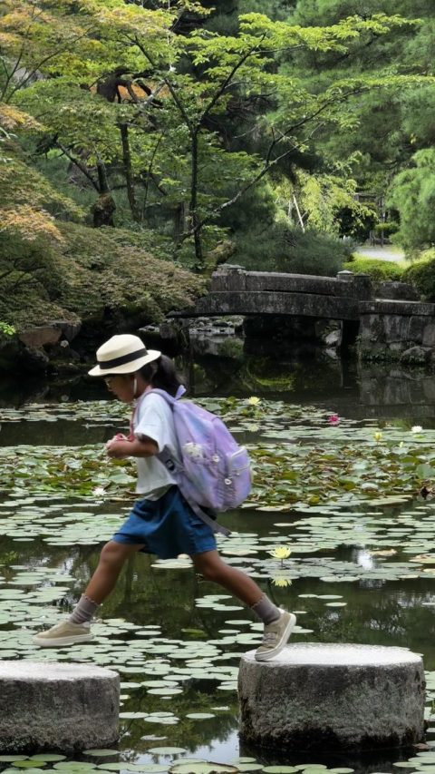귀여운 일본 아이가 돌다리 건너고 있다.